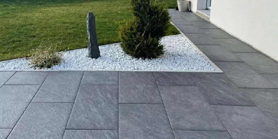 Am&eacute;nagement paysager ext&eacute;rieur avec bordure d&eacute;corative en blocs de b&eacute;ton textur&eacute; marron d&eacute;limitant un massif v&eacute;g&eacute;tal