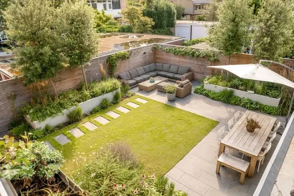 Cour méditerranéenne avec escaliers en pierre naturelle, végétation luxuriante incluant bougainvilliers violets, palmiers et arbustes verts