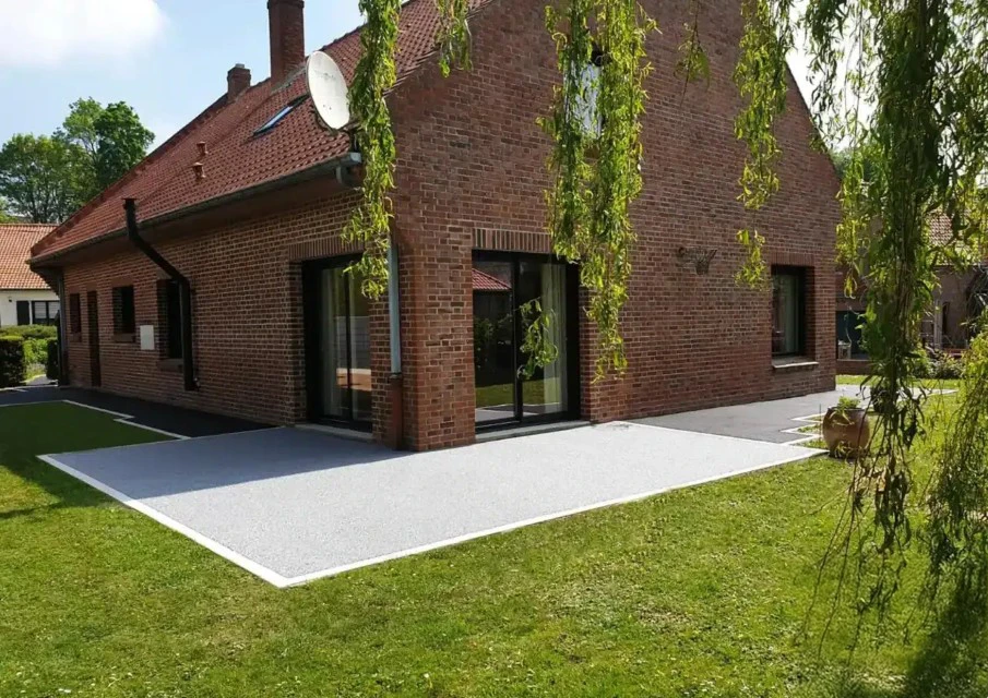 Terrasse extérieure moderne avec mobilier de jardin noir en résine tressée sur dallage pierre naturelle