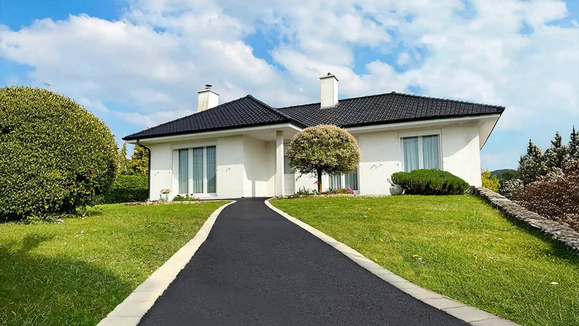 Escalier extérieur en pierre naturelle avec emmarchement élargi, menant à l'entrée d'un bâtiment blanc