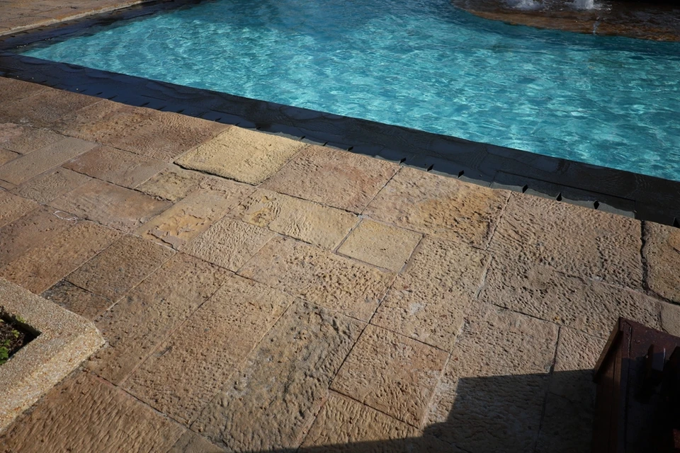 Pierre granit sur terrasse avec la piscine bleue